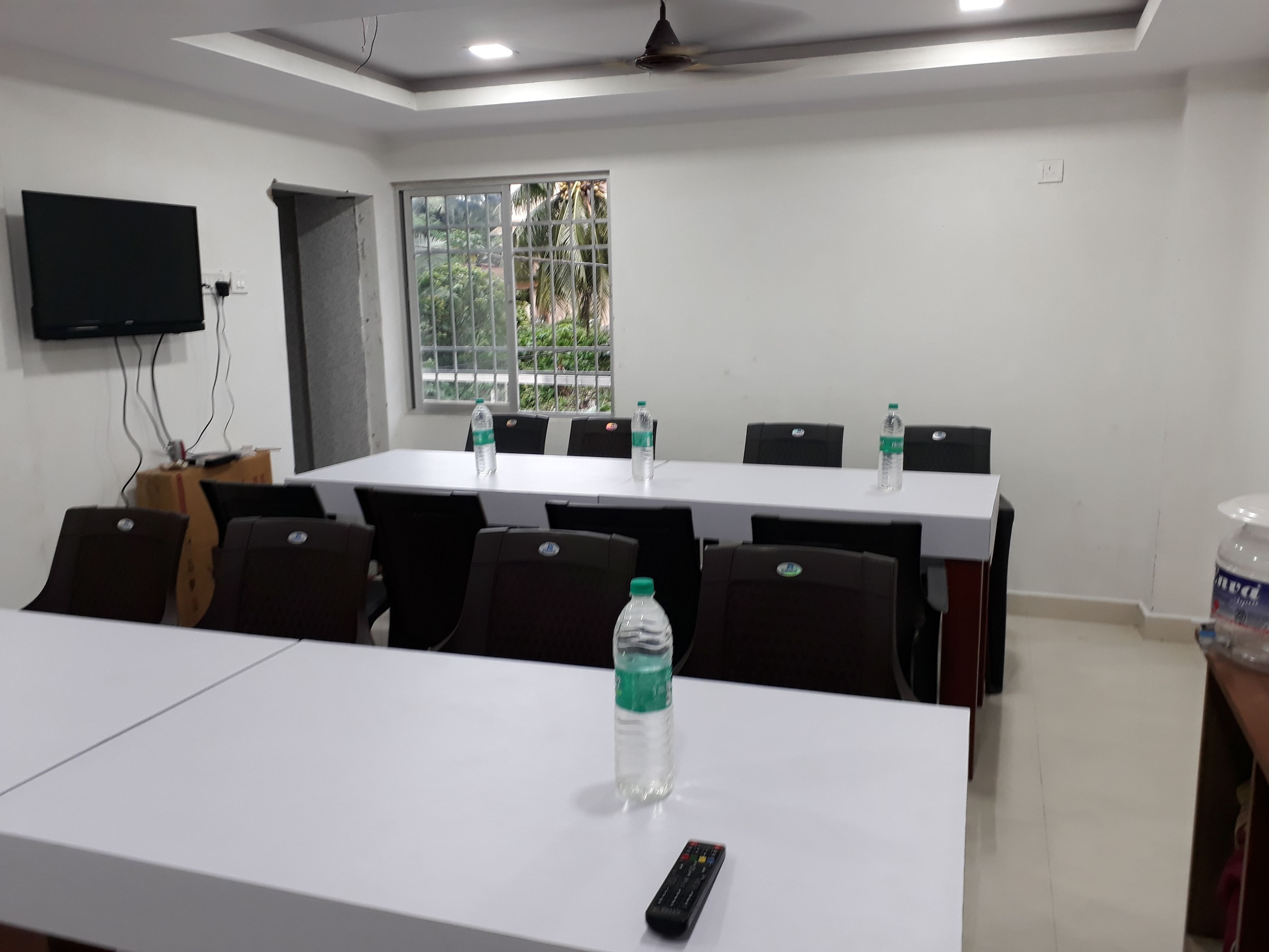 A conference room with a long table, chairs, a television, and water bottles.