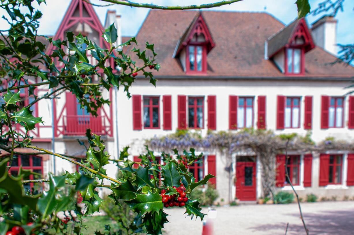 Un bâtiment traditionnel avec des volets rouges et une façade blanche, caractérisé par un toit rouge bien visible et une petite tour.