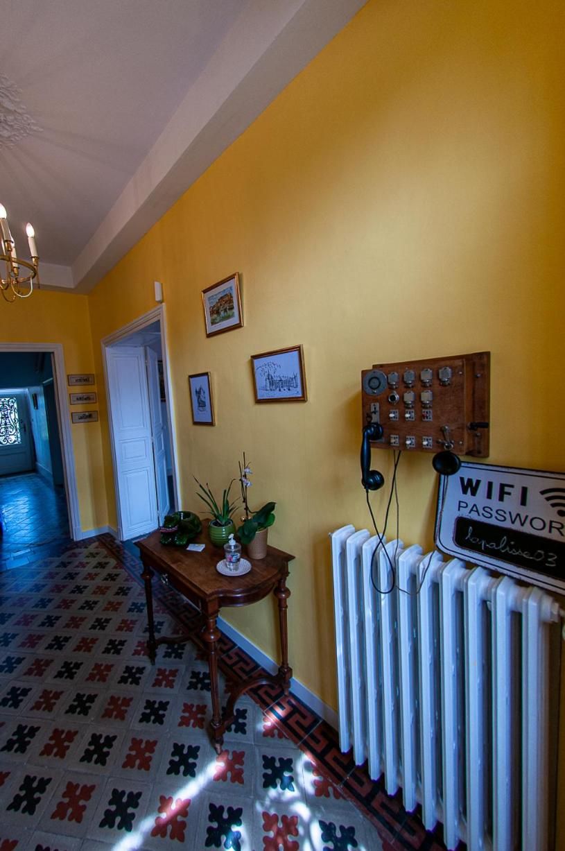 A hallway with a radiator, a wooden table with a plant, and a sign indicating a WiFi password.