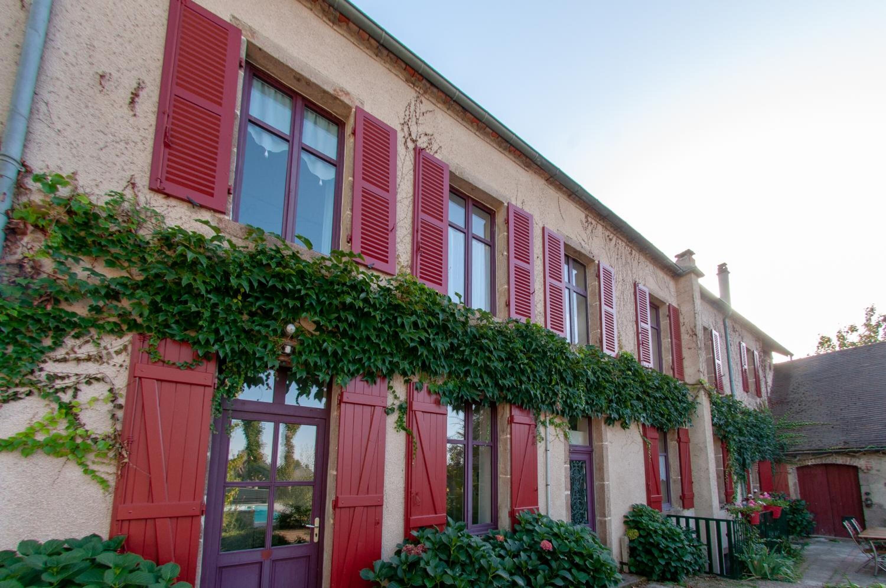 Un edificio con persianas rojas y fachada cubierta de hiedra.