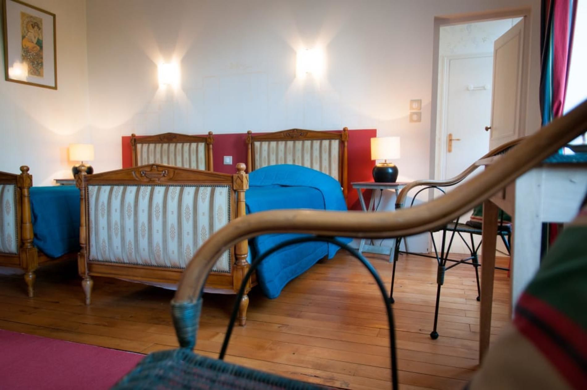 Ein Schlafzimmer mit einem hölzernen Bett, einem blauen Sessel und Holzboden.