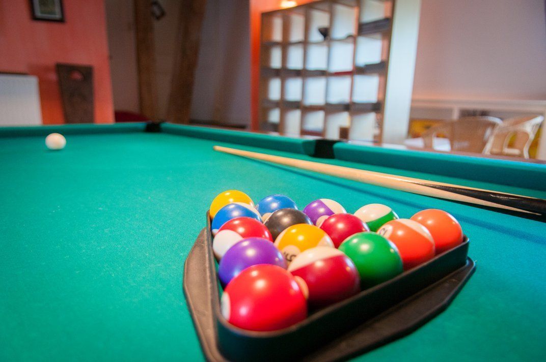 A pool table with a rack of colorful balls and a cue stick.