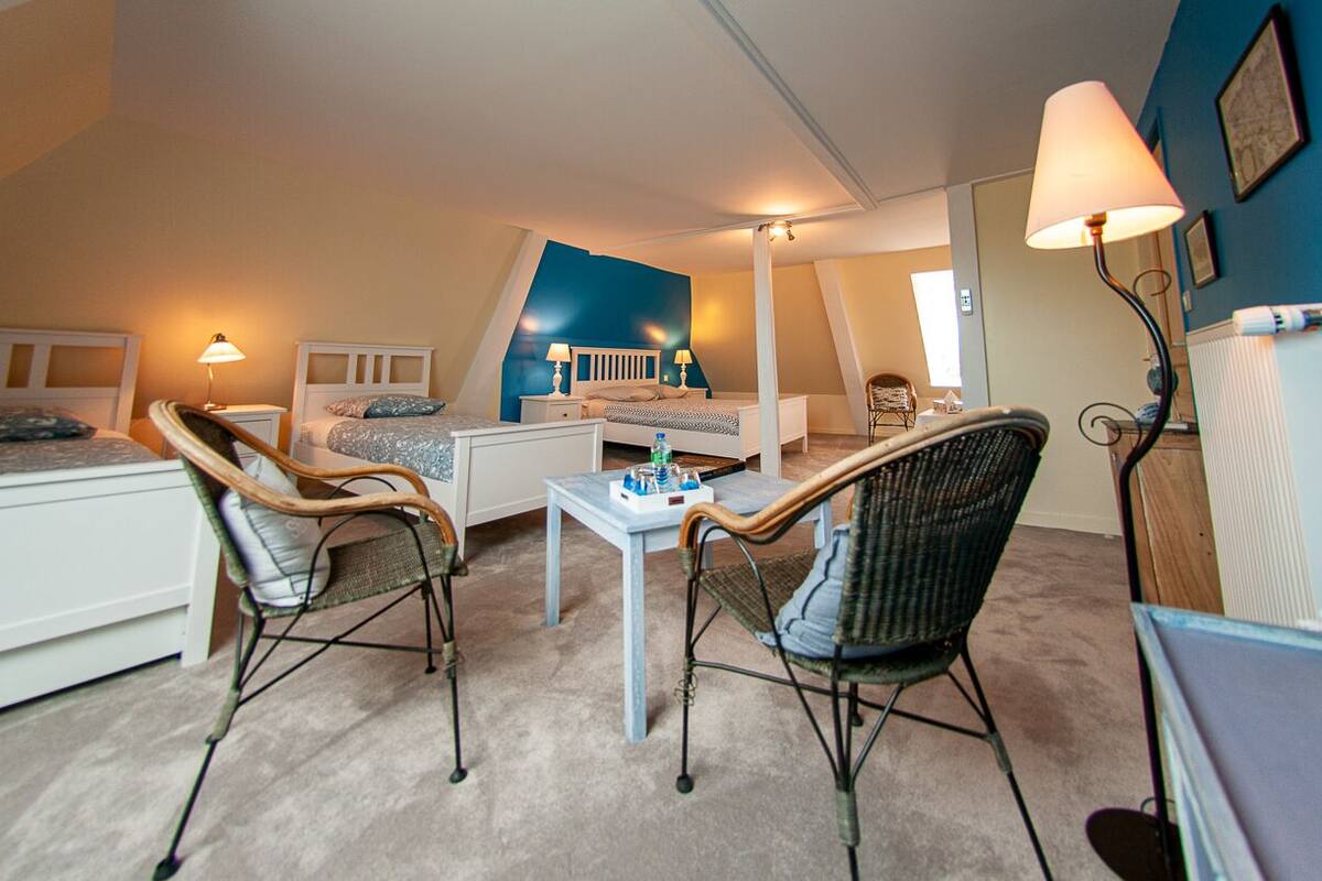 A bedroom with a bed, two chairs, a table, and a lamp.