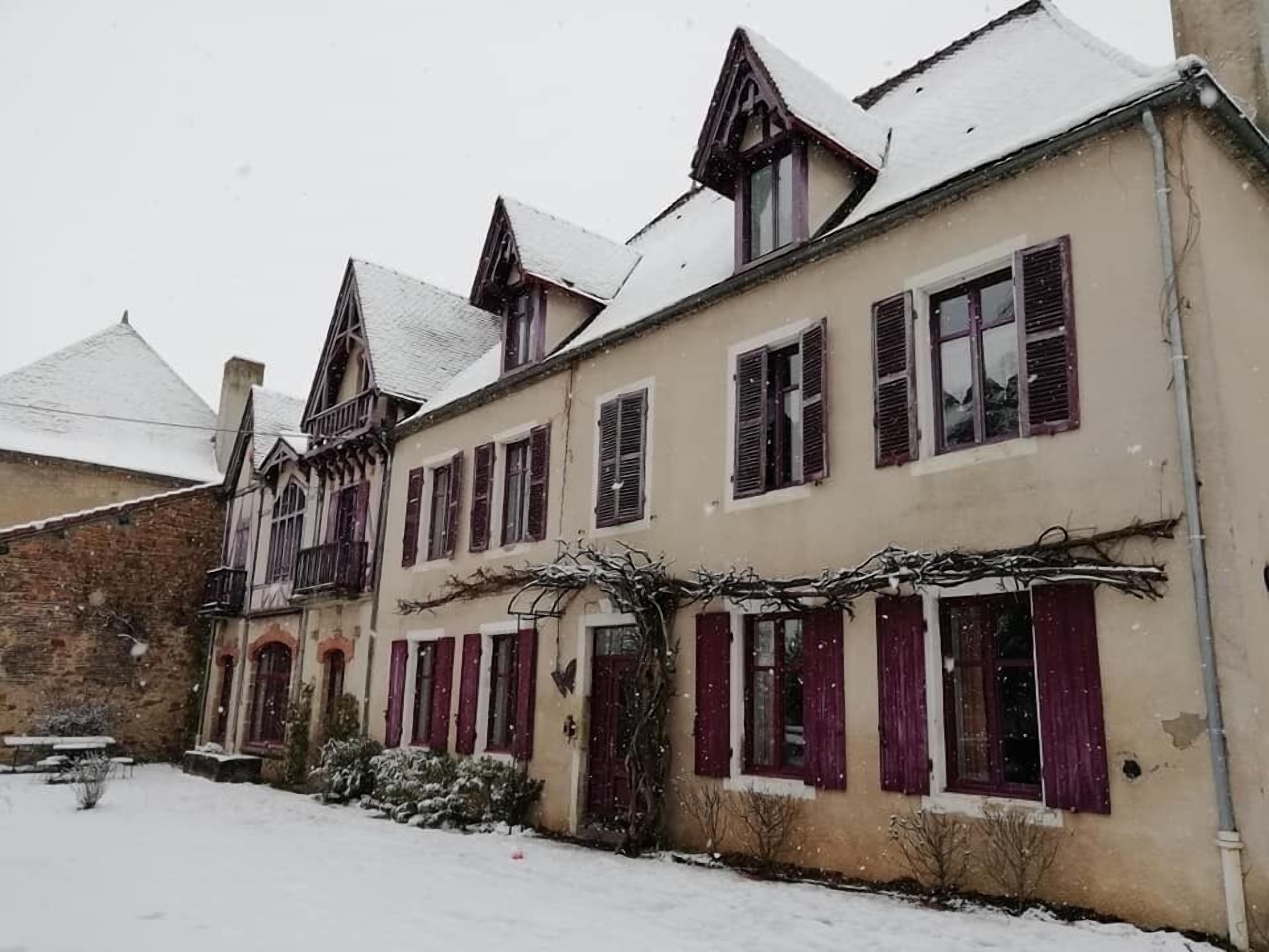 Un edificio tradicional con múltiples ventanas y un techo cubierto de nieve.