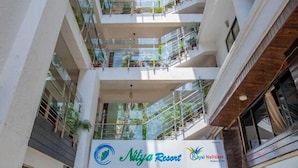 A multi-level hotel atrium with balconies, a checkered floor, and potted plants. - Nitya Resort (Calangute)