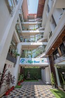 A multi-level hotel atrium with balconies, a checkered floor, and potted plants.