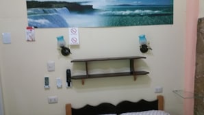 A bedroom with a bed, a wall-mounted shelf, a painting of a waterfall, and a 'No Smoking' sign. - CASA GLORIA (Santiago de Cuba)