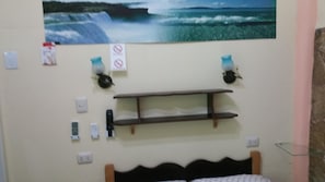A bedroom with a bed, a wall-mounted shelf, a painting of a waterfall, and a 'No Smoking' sign. - CASA GLORIA (Santiago de Cuba)