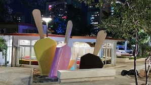A public space with a colorful sculpture and a building with illuminated signage in the background. - CASA GLORIA (Santiago de Cuba)