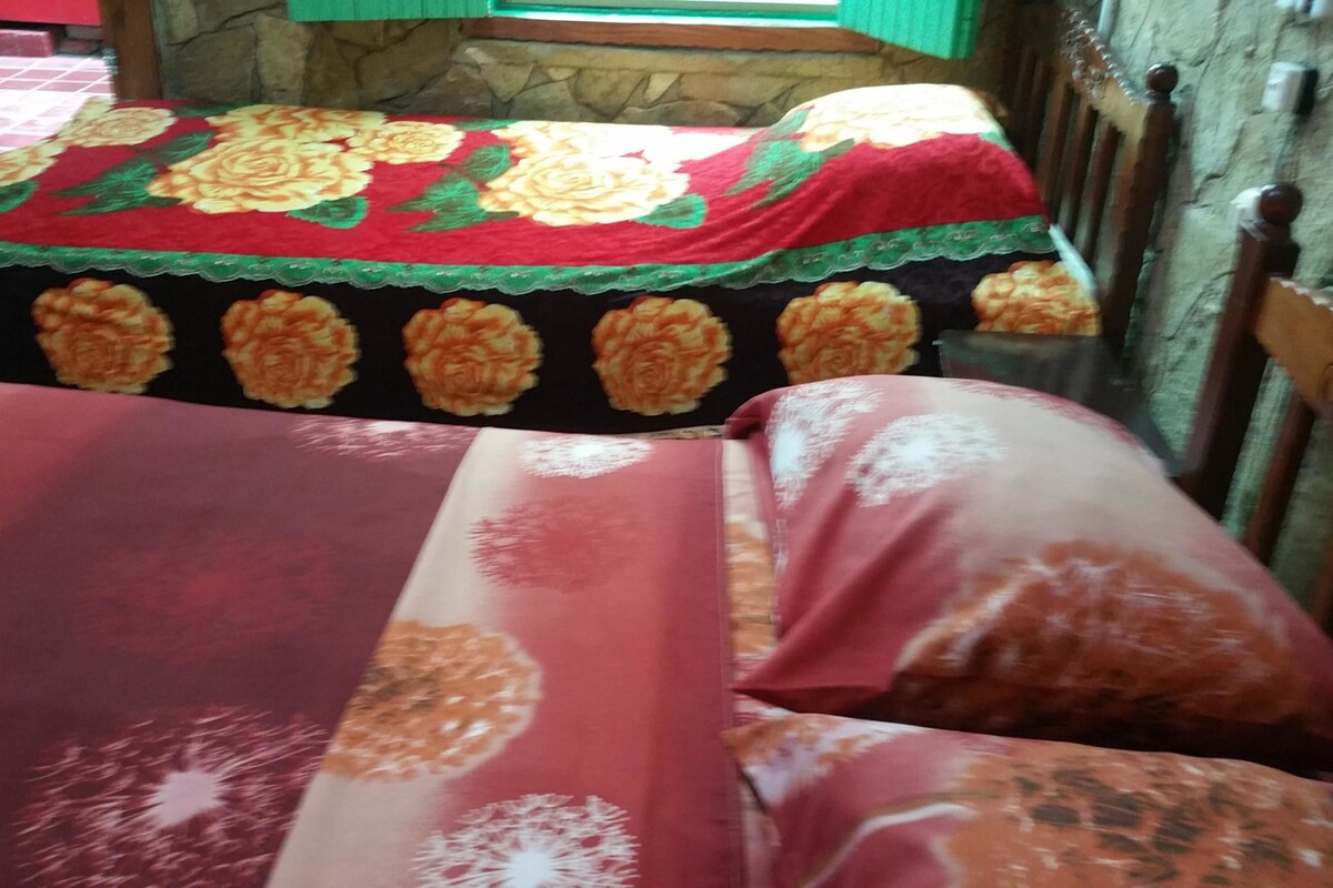 A bed with floral bedspreads and a stone wall in the background.