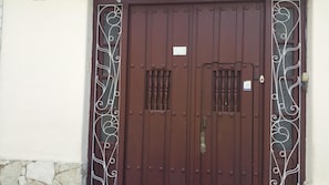 A brown double door with decorative metalwork and a small sign above the door. - CASA GLORIA (Santiago de Cuba)