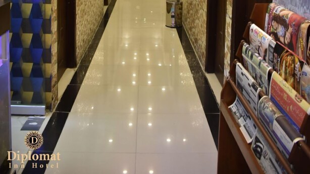 A hotel corridor with a polished floor, patterned walls, and a ceiling with recessed lighting.