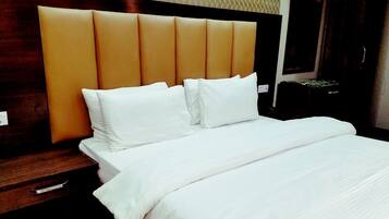 A neatly made bed with white linens and a headboard with vertical panels.