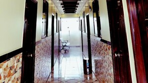 A hallway with a modern ceiling design, marble flooring, and doors on both sides.
