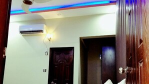 A bedroom with a bed, a ceiling fan, an air conditioning unit, and a door.