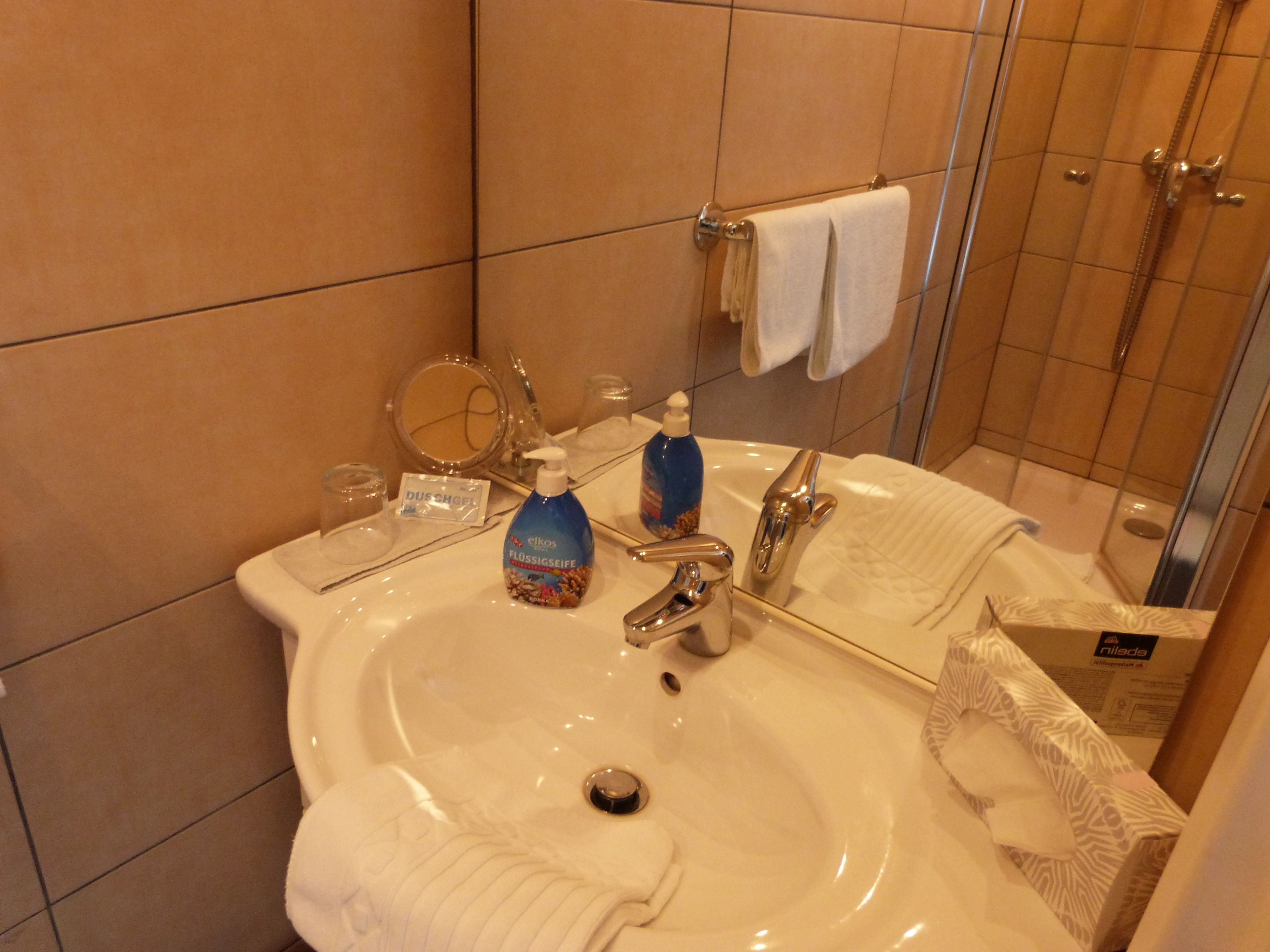 A bathroom with a sink, mirror, and toiletries.