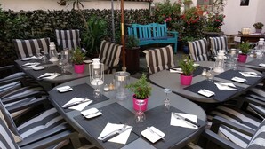 A well-set outdoor dining area with multiple tables and chairs, potted plants, and a blue bench. - Hotel Restaurant Jägerhof (Mayen)
