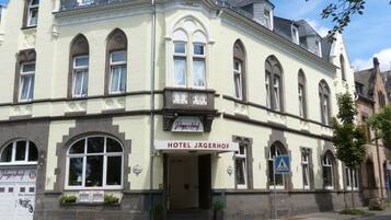 Hotel Jägerhof features a historic tower and traditional architecture, with a large entrance and potted plants at the base.