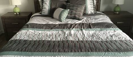 A bed with a patterned quilt, two pillows, and two bedside tables with lamps.