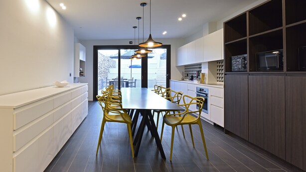 Una cocina moderna con una mesa de comedor grande, sillas amarillas y armarios empotrados.