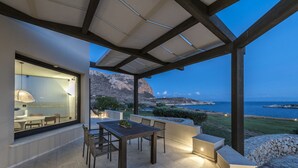 Un patio exterior con mesa y sillas, una pérgola y vistas al mar y a las montañas.