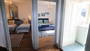 Une chambre avec deux lits, un grand miroir et un lustre.