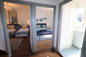 Quarto com duas camas, um espelho grande e um lustre.