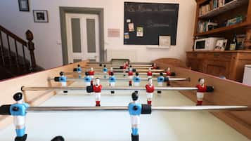 Relax and have fun in this room, featuring a foosball table and a cozy reading nook with a bookshelf.