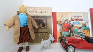 Ein Regal mit einem Buch mit dem Titel 'Conte de Noël' von Charles Dickens, einem Spielzeughund und einem Spielzeugauto.
