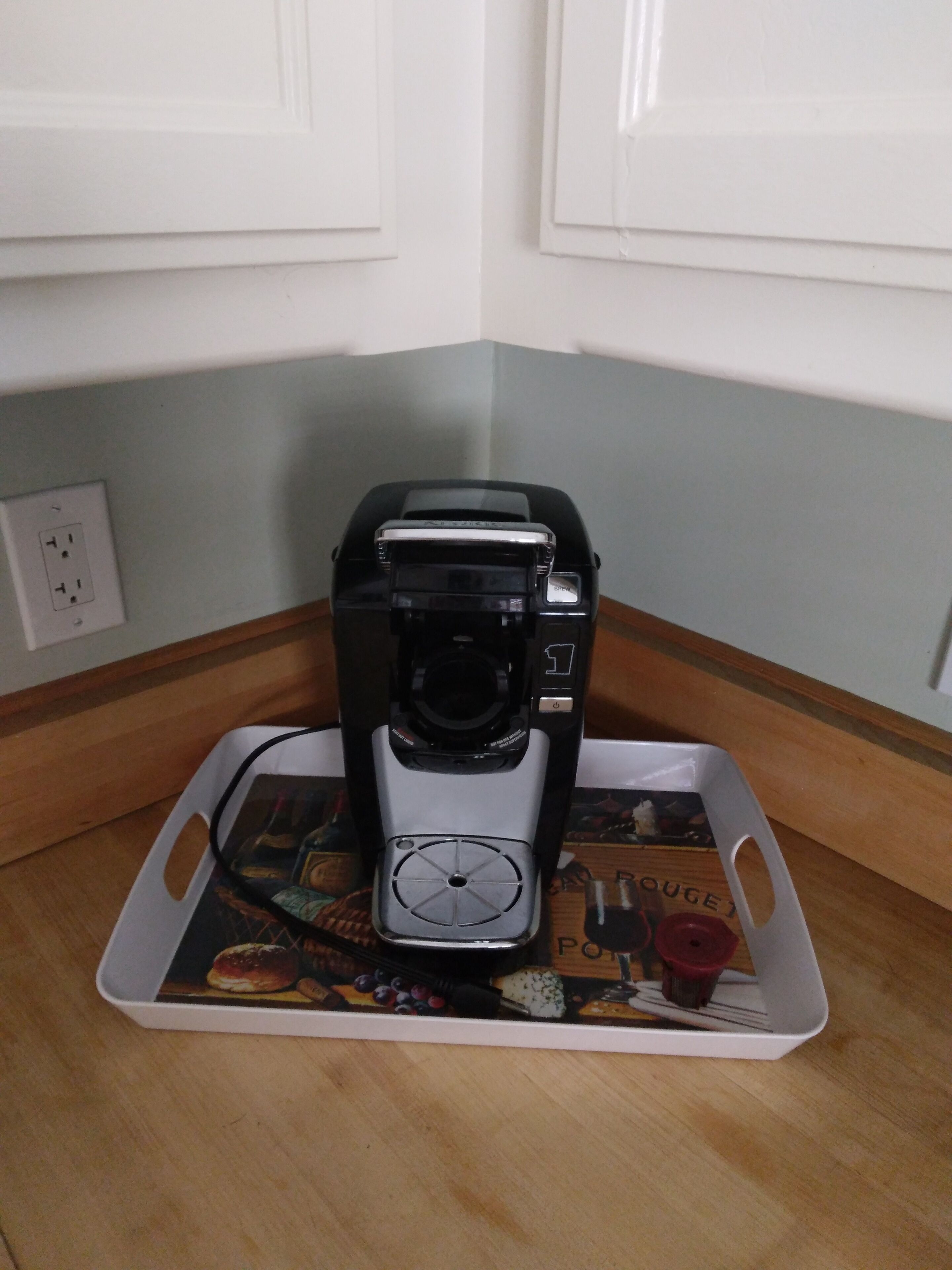 A coffee maker on a tray with a picture of food items.