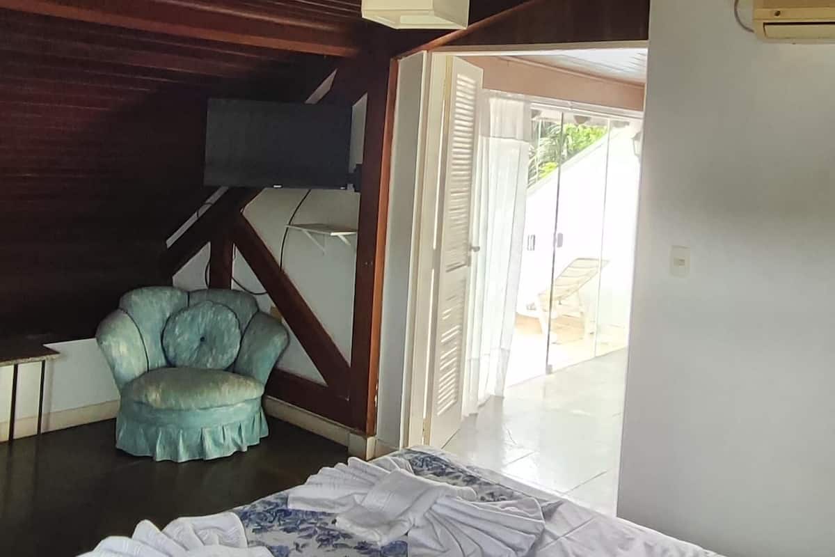 Ein Zimmer mit einem Bett, einem Sessel und einem Deckenventilator.