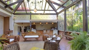 Un patio interior con mobiliario de madera, un techo con diseño geométrico y vistas a zonas verdes.