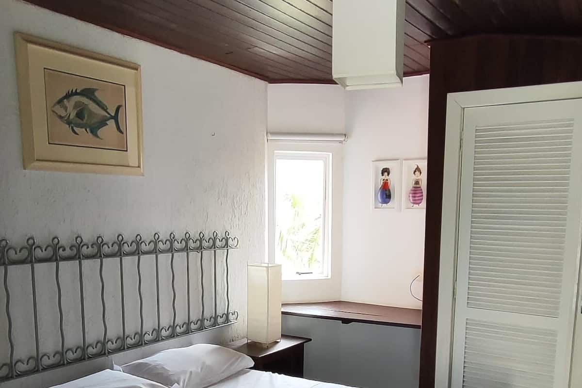 Ein Schlafzimmer mit einem Bett, einem Nachttisch, einem Fenster und einer Tür.