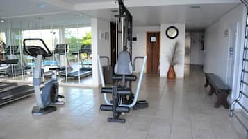 Ein Fitnessraum mit Trainingsgeräten, einer Bank und einem Topf mit Pflanze.