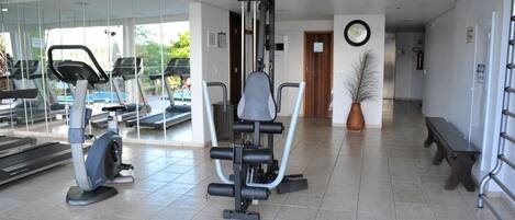 A gym with exercise equipment, a bench, and a potted plant.