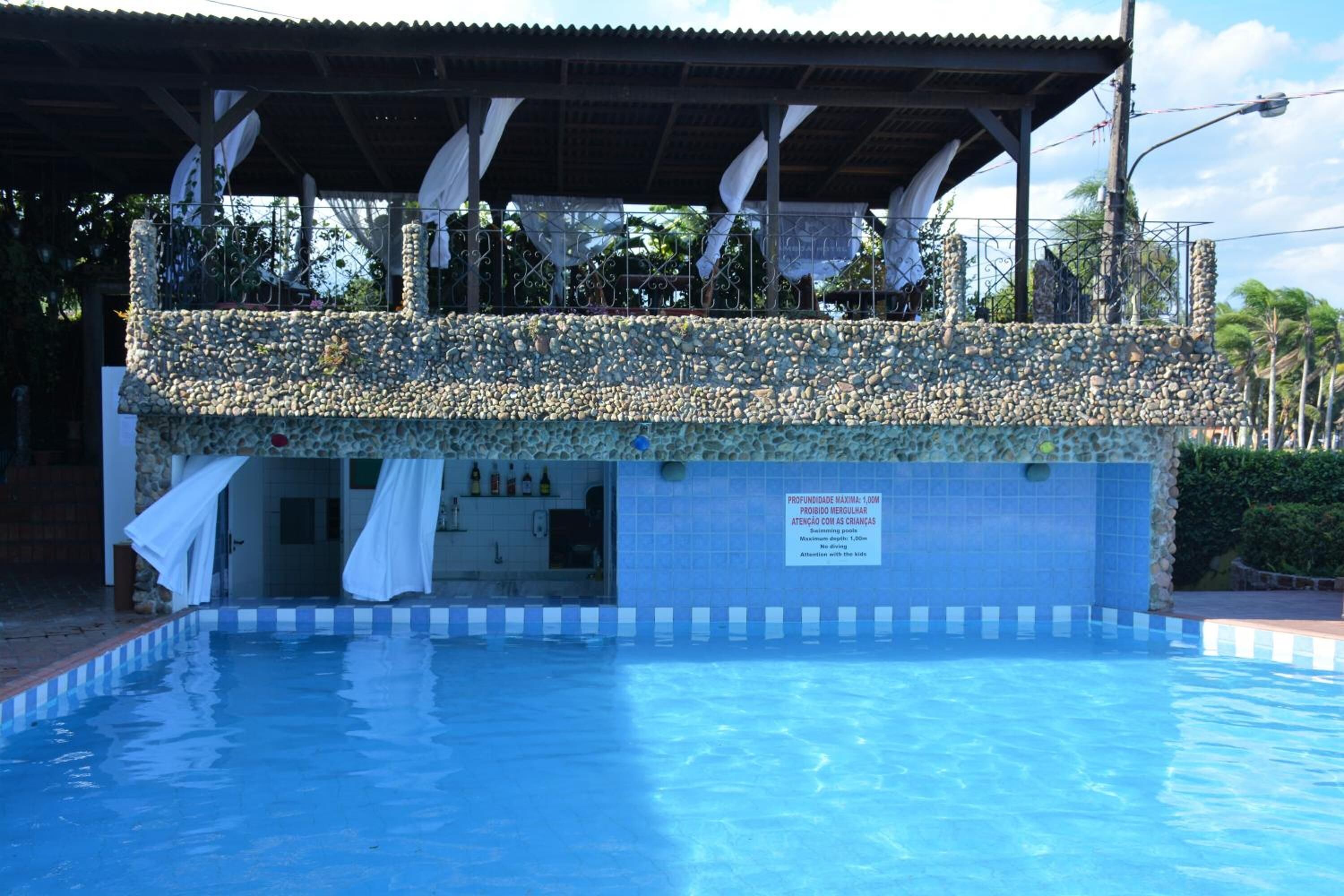 A swimming pool with a covered area decorated with stones and white drapes.