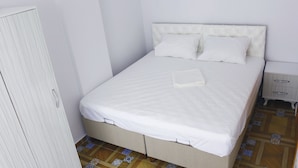 A neatly made bed with white linens, a wooden wardrobe, and a small bedside table with a drawer. - Mercan Suite Hotel (Gökçeada)