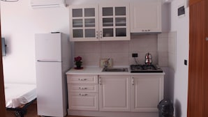 A compact kitchen with white cabinets, a refrigerator, a sink, and a stove. - Mercan Suite Hotel (Gökçeada)