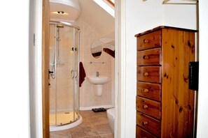 A bathroom with a glass-enclosed shower, a sink, and a wooden cabinet.