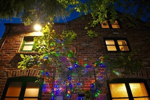 A brick building with two windows and a tree in front.
