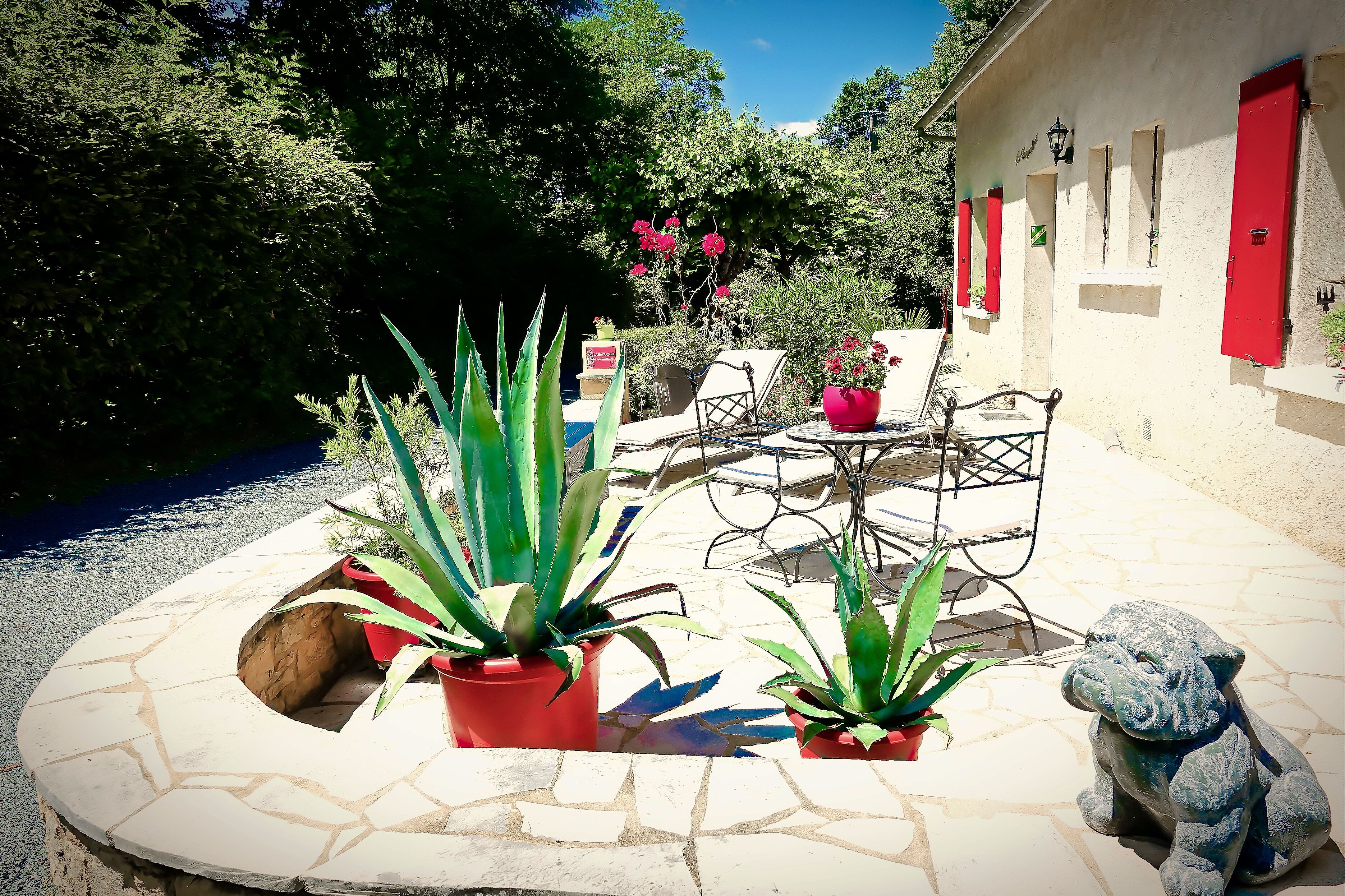 Un patio con plantas en macetas, mobiliario exterior y un camino de piedra.