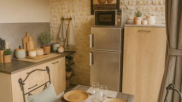 Una cocina acogedora con pared de piedra, techo de madera y una zona de comedor con una mesa dispuesta para dos.