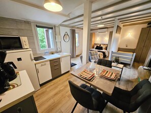 Cocina moderna con microondas, cafetera y comedor con una mesa dispuesta para dos.