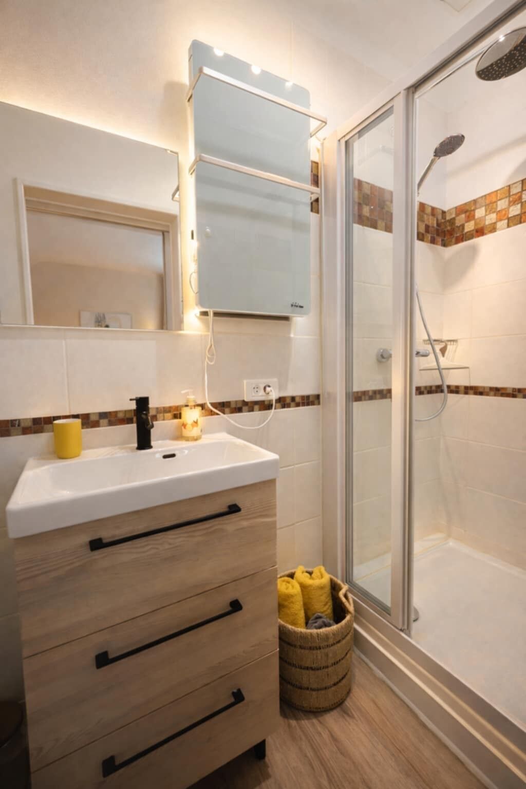 A bathroom with a white sink, wooden cabinet, and a glass shower enclosure.