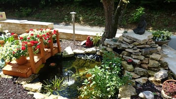 A garden with a pond, stone steps, and a Buddha statue.