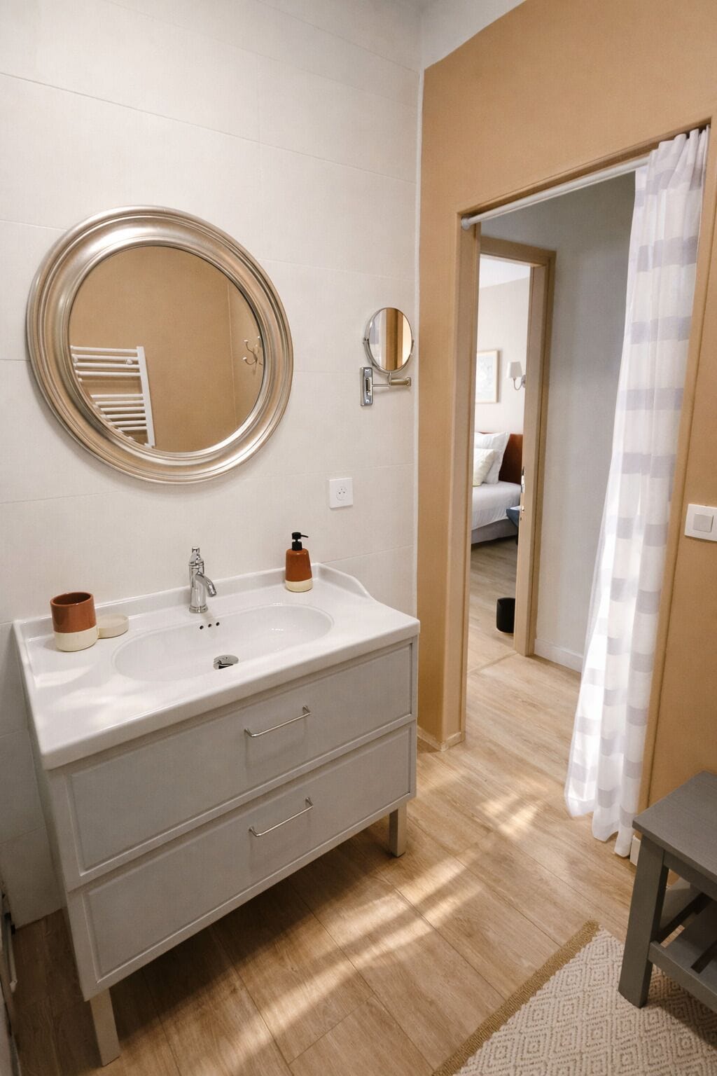 A bathroom with a white vanity, a round mirror, a small round mirror, and a shower curtain.
