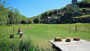Una persona sentada en un banco en un campo cubierto de hierba, con un castillo al fondo.