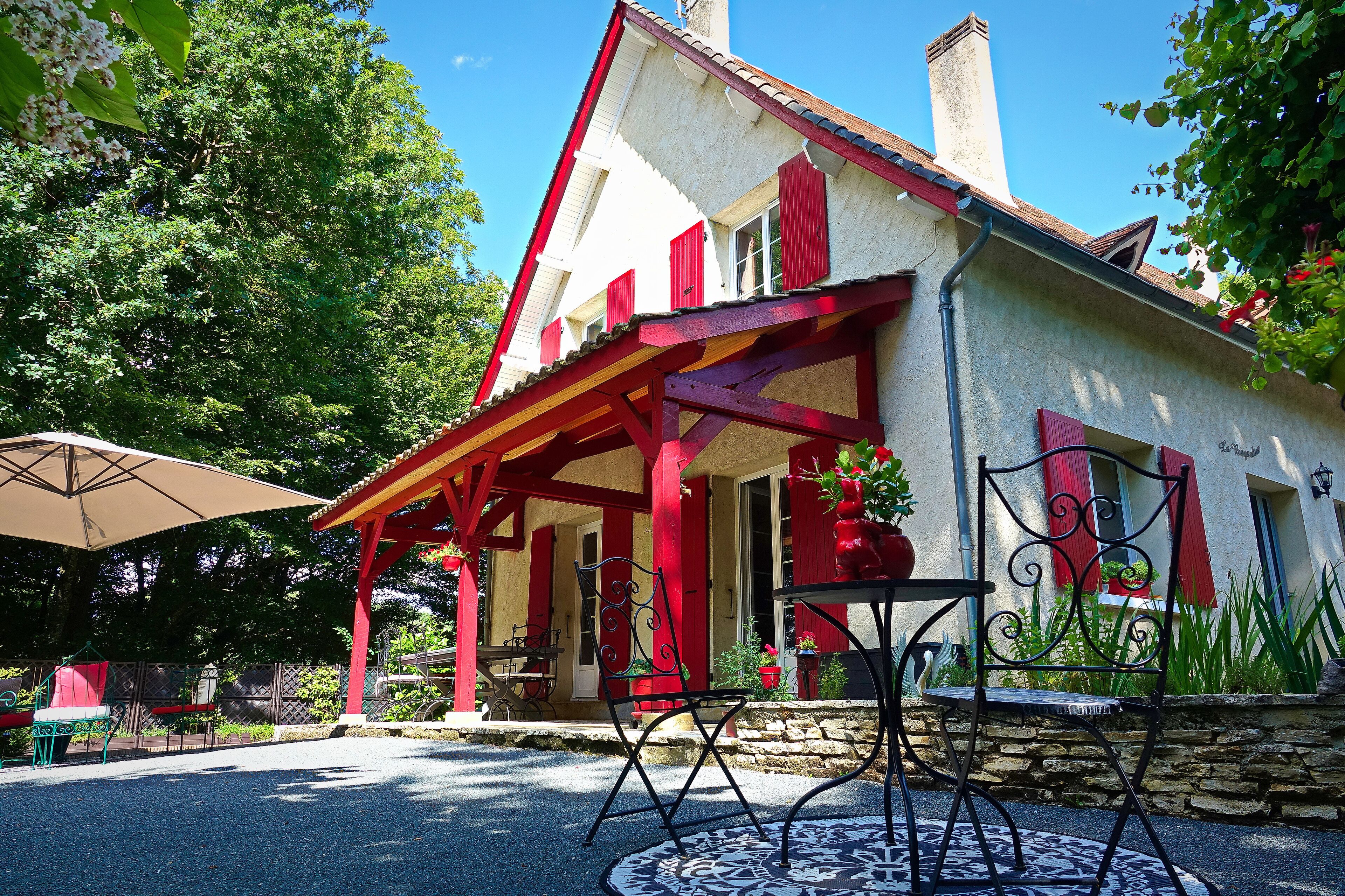 A house with a porch, outdoor seating, and a stone wall.