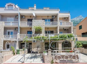 A multi-story building with balconies, air conditioning units, and a stone facade. - Ivana Apartments (Makarska)