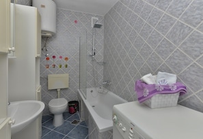 A bathroom with a toilet, sink, bathtub, and a shower. - Ivana Apartments (Makarska)
